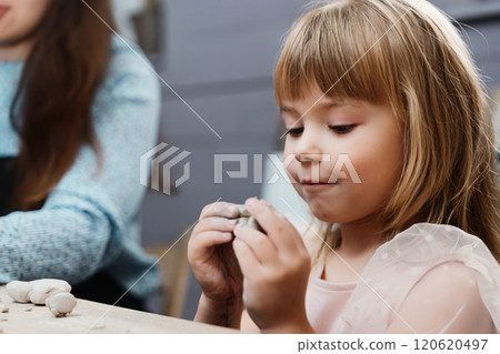 A child molds clay with concentration during a creative workshop indoors A child molds clay with concentration during a creative workshop indoors 120620497