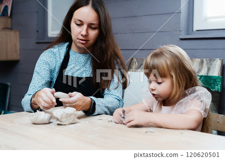 Creative mother and daughter clay modeling session at home in afternoon light 120620501