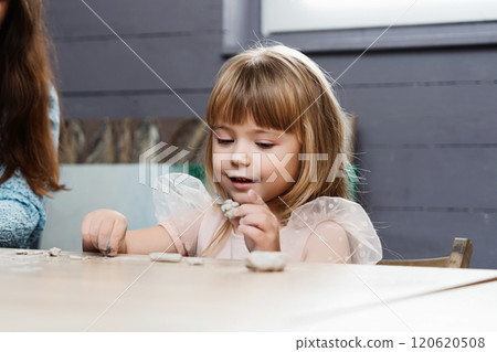 A girl engages in clay sculpting activity indoors during the daytime 120620508