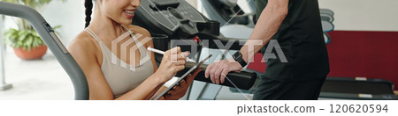 Smiling Trainer Recording Workout Data with Client Smiling Trainer Recording Workout Data with Client 120620594