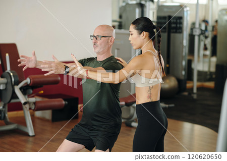 Personal Trainer Guiding Man in Gym Session 120620650