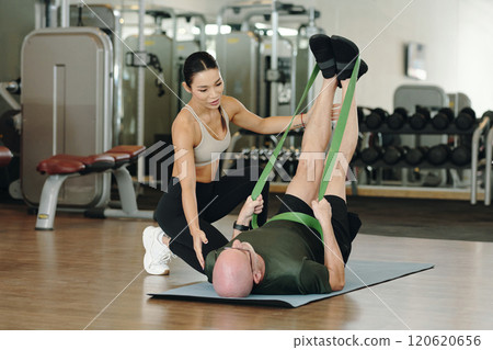 Assisting Elderly Man Exercising with Resistance Bands Assisting Elderly Man Exercising with Resistance Bands 120620656