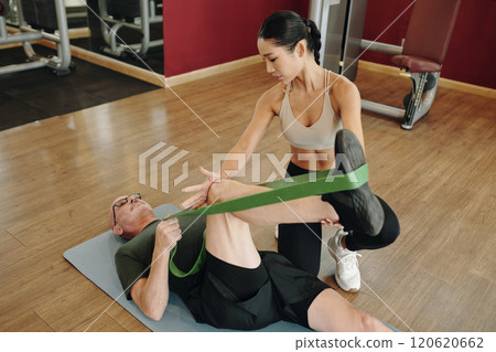 Female Trainer Assisting Client with Stretching Exercise Female Trainer Assisting Client with Stretching Exercise 120620662