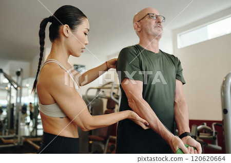 Assisting Senior Man with Exercising at Gym Assisting Senior Man with Exercising at Gym 120620664