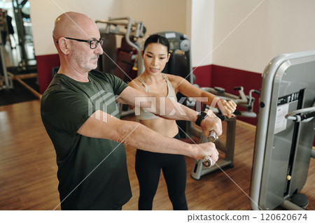 Assisting Senior Male with Gym Equipment Workout 120620674