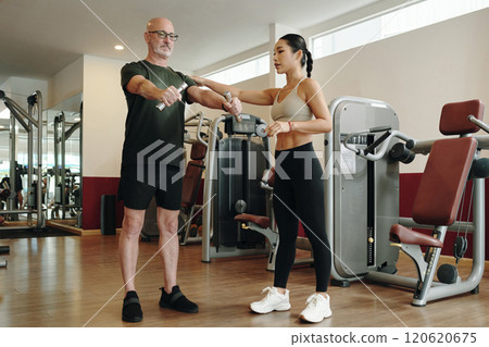 Personal Trainer Assisting Man during Gym Workout Session Personal Trainer Assisting Man during Gym Workout Session 120620675
