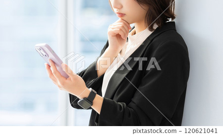 Woman/businesswoman thinking while looking at her smartphone 120621041