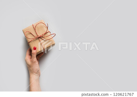 Christmas craft gift box in woman hand on neutral gray. Zero waste holiday. Xmas greeting card. Boxing day. Christmas craft gift box in woman hand on neutral gray. Zero waste holiday. Xmas greeting card. Boxing day. 120621767