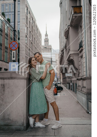Happy couple of tourists walking embraced while sightseeing the town. Happy couple in front of palace of culture and science in Warsaw, Poland. Close up of a couple kissing. Happy couple of tourists walking embraced while sightseeing the town. Happy couple in front of palace of culture and science in Warsaw, Poland. Close up of a couple kissing. 120622303