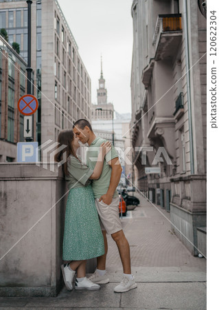 Happy couple of tourists walking embraced while sightseeing the town. Happy couple in front of palace of culture and science in Warsaw, Poland. Close up of a couple kissing. 120622304