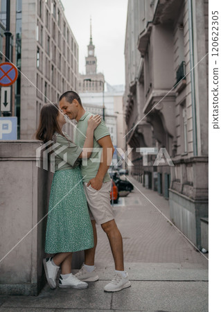Happy couple of tourists walking embraced while sightseeing the town. Happy couple in front of palace of culture and science in Warsaw, Poland. Close up of a couple kissing. Happy couple of tourists walking embraced while sightseeing the town. Happy couple in front of palace of culture and science in Warsaw, Poland. Close up of a couple kissing. 120622305