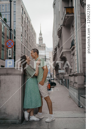 Happy couple of tourists walking embraced while sightseeing the town. Happy couple in front of palace of culture and science in Warsaw, Poland. Close up of a couple kissing. Happy couple of tourists walking embraced while sightseeing the town. Happy couple in front of palace of culture and science in Warsaw, Poland. Close up of a couple kissing. 120622306