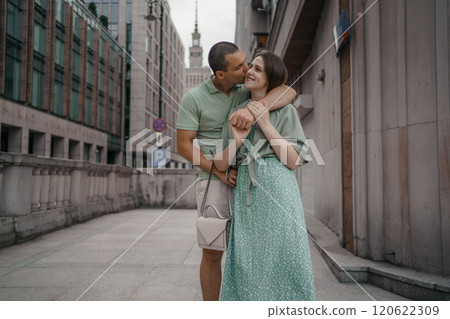 Happy couple of tourists walking embraced while sightseeing the town. Happy couple in front of palace of culture and science in Warsaw, Poland. Close up of a couple kissing. Happy couple of tourists walking embraced while sightseeing the town. Happy couple in front of palace of culture and science in Warsaw, Poland. Close up of a couple kissing. 120622309