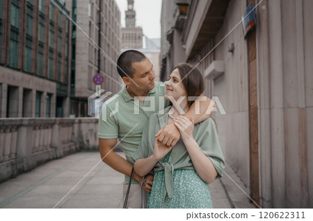 Happy couple of tourists walking embraced while sightseeing the town. Happy couple in front of palace of culture and science in Warsaw, Poland. Close up of a couple kissing. 120622311