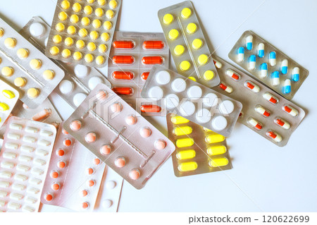 Various medication capsules, tablets are spread out on white surface, showcasing different shapes collection highlights diversity in pharmaceuticals. 120622699