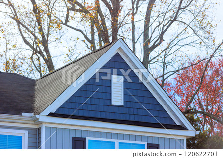 Reveals elegant design of gray house highlighting shingles on roof surrounding, unique architectural details 120622701