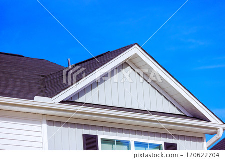 Sloped roof features stylish shingles light colored siding, presenting contemporary architectural design against composition captures sense of tranquility. 120622704