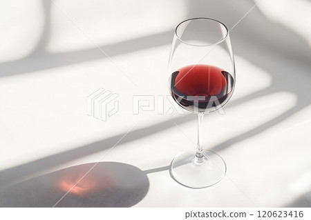Glass of red wine casting shadow on white background Glass of red wine casting shadow on white background 120623416