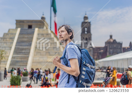 Male tourist standing in front of the Metropolitan Cathedral of Mexico City, a Mayan pyramid, and the Mexican flag. Cultural heritage, travel, and iconic landmarks concept 120623550