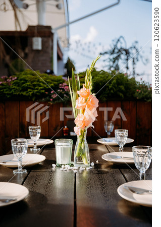 Elegant table setting with gladiolus flowers in vase under natural light, perfect for outdoor dining Elegant table setting with gladiolus flowers in vase under natural light, perfect for outdoor dining 120623590