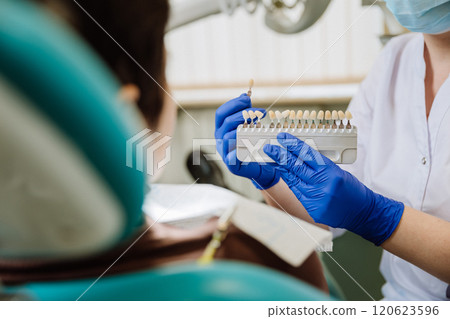 Dentist selecting a shade for dental veneers to ensure a perfect match for the patient's teeth 120623596