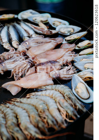 Fresh seafood selection on the grill, including squid, shrimp, mussels, and fish, ready for cooking Fresh seafood selection on the grill, including squid, shrimp, mussels, and fish, ready for cooking 120623618