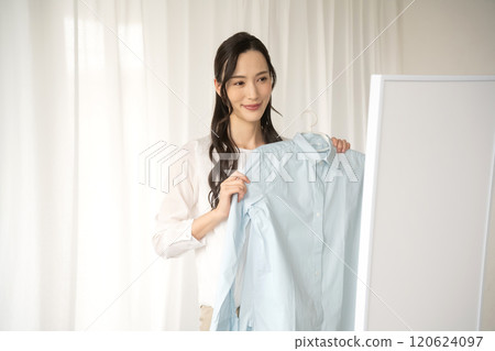 年輕女子在室內選擇衣服 120624097