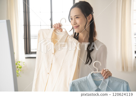 年輕女子在室內選擇衣服 120624119