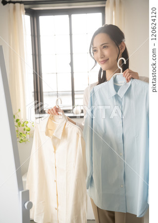 年輕女子在室內選擇衣服 120624120