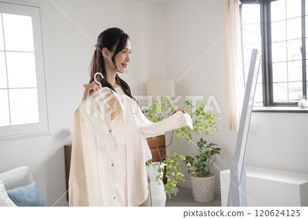 Young woman choosing clothes indoors 120624125