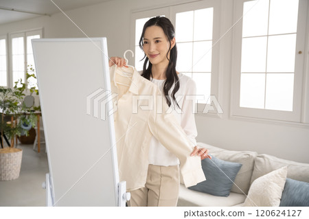 年輕女子在室內選擇衣服 120624127