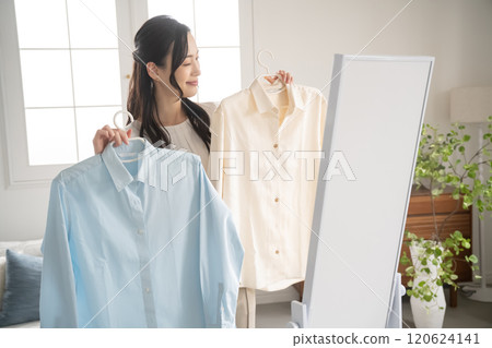Young woman choosing clothes indoors Young woman choosing clothes indoors 120624141