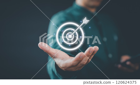 A businessman holds a glowing digital target with an arrow in the center, symbolizing focus and goal achievement. The futuristic design highlights innovation and success. A businessman holds a glowing digital target with an arrow in the center, symbolizing focus and goal achievement. The futuristic design highlights innovation and success. 120624375