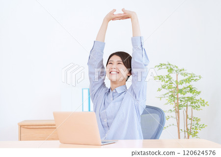 A woman stretching while working at a computer A woman stretching while working at a computer 120624576