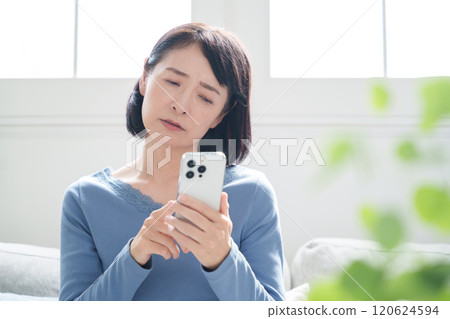中年婦女一邊看著智慧型手機一邊思考 120624594