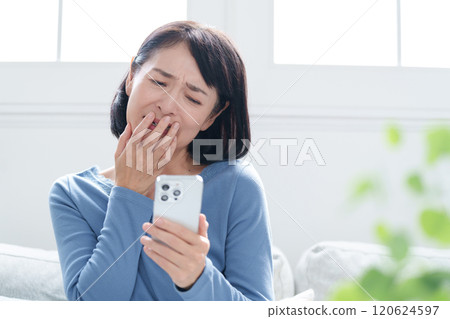 中年婦女一邊看著智慧型手機一邊思考 120624597