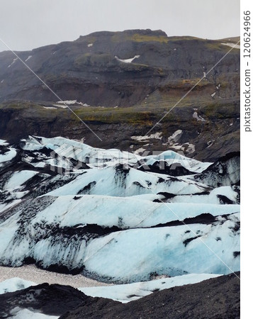 Glacier vatnajokull cracked ice mass in iceland with cracked icy rocks melting due to global warming, icelandic scenic route. Fantastic arctic icebergs near brown frozen hills. Glacier vatnajokull cracked ice mass in iceland with cracked icy rocks melting due to global warming, icelandic scenic route. Fantastic arctic icebergs near brown frozen hills. 120624966