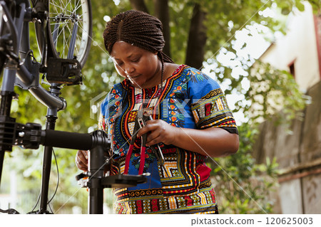 Active focused black woman preparing necessary expert tools for repairing broken bicycle tire. Sporty african american female grasping various specialized equipment for servicing damaged bike. Active focused black woman preparing necessary expert tools for repairing broken bicycle tire. Sporty african american female grasping various specialized equipment for servicing damaged bike. 120625003