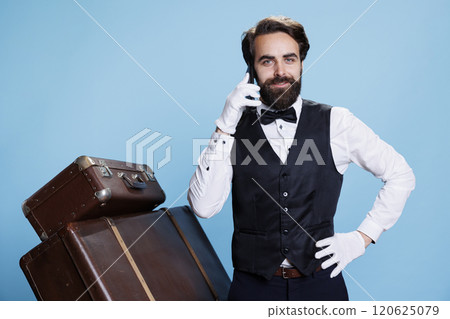 Hotel porter answer phone call in studio, accepting reservations through telephone line. Professional classy doorkeeper employee having remote chat, booking inquiries and services. Hotel porter answer phone call in studio, accepting reservations through telephone line. Professional classy doorkeeper employee having remote chat, booking inquiries and services. 120625079
