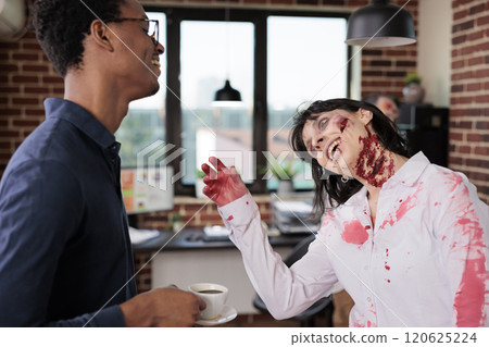 Happy employee wearing zombie costume with cheerful manager in office laughing. African american boss and woman dressed as scary monster having fun during Halloween event at work Happy employee wearing zombie costume with cheerful manager in office laughing. African american boss and woman dressed as scary monster having fun during Halloween event at work 120625224