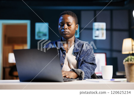 African american female student utilizing modern technology for studying online, research and projects. Serious freelancer using digital laptop for browsing the internet and respond to emails. 120625234