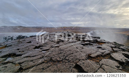 Massive river stream falling down hillside and edges in Icelandic region creating nordic Gullfoss waterfall. Fantastic wintry scenery with freezing cold water in arctic landscape running off cliffs. 120625350