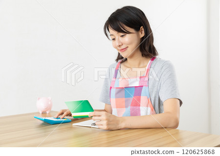 家庭主婦看著銀行存摺併計算01 120625868