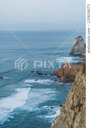 Coastal view with rocky cliffs and tranquil ocean at sunset 120626073