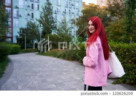 Young woman with vibrant red hair poses outdoors in a pink blazer Young woman with vibrant red hair poses outdoors in a pink blazer 120626209