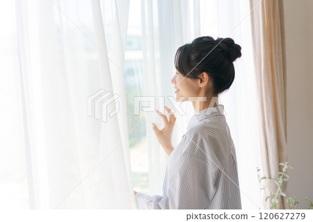 Woman opening curtain Woman opening curtain 120627279