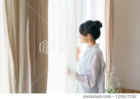 Woman opening curtain 120627282