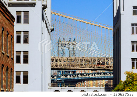 Picturesque view Manhattan Bridge nestled between two historic buildings scene showcases architecture, engineering marvel. 120627552