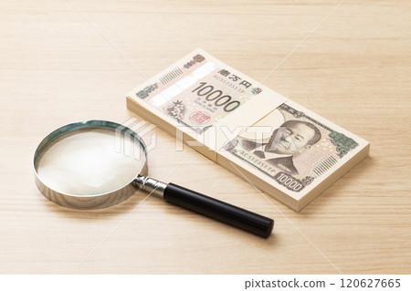 1 million yen and a magnifying glass on a table 120627665
