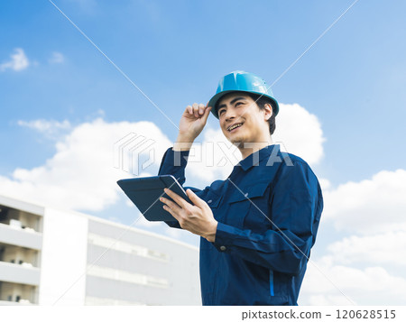 A male worker using a tablet PC in front of a building 120628515